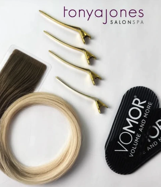 A set of hair extension tools and products, including hair wefts, four gold clips, and VOMOR branding, with the Tonya Jones SalonSpa logo at the top. - Tonya Jones SalonSpa| Birmingham, AL
